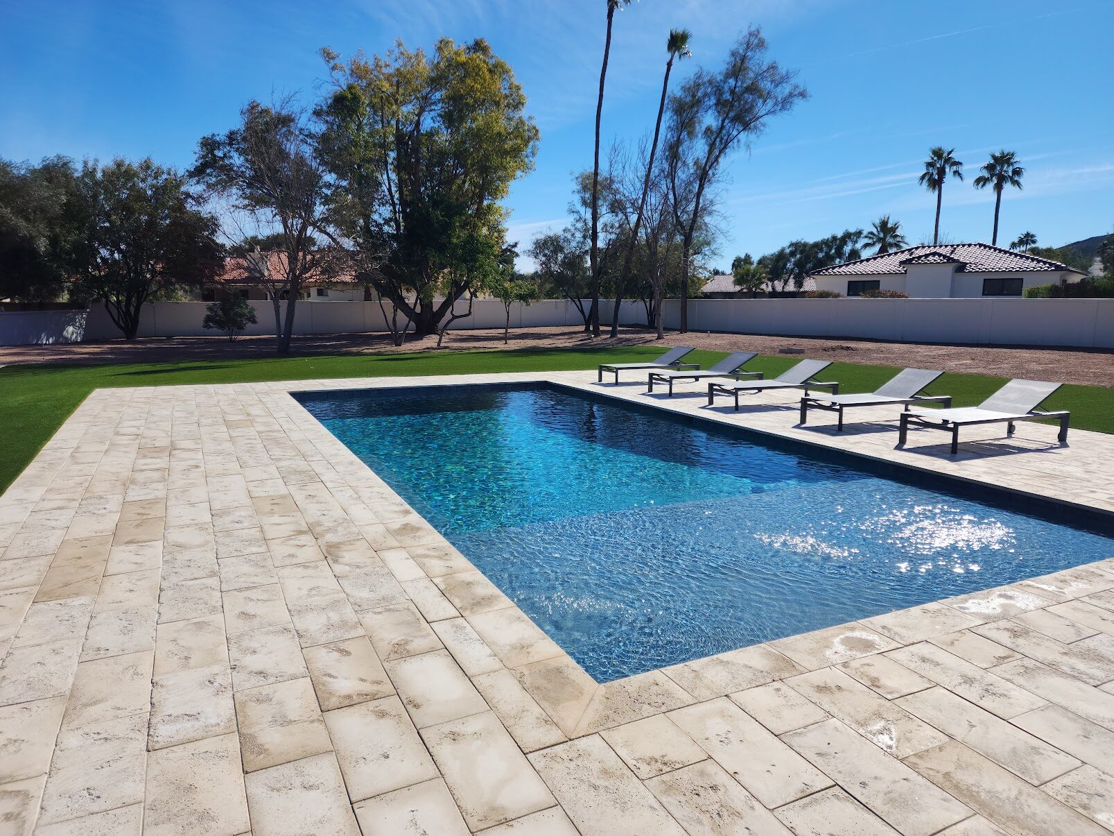 Luxury pool transformation with travertine deck, modern lounge area, and desert landscaping in Paradise Valley